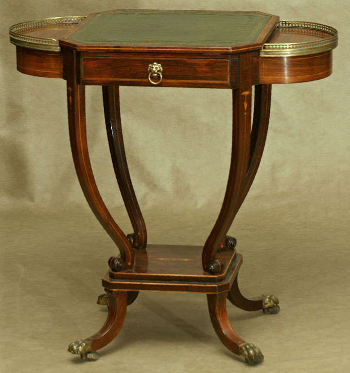 A delicate and airy little table with great eye appeal. The central adjustable top is covered in gilt tooled leather. Two side compartments are for storage, inkwells and writing implements. It has a single drawer on one side.